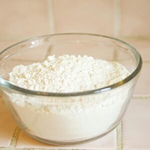 Close-up of a glass bowl filled with white flour, a common baking ingredient.