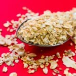 Close-up image of oats scattered on a spoon with vivid red background, perfect for food advertising.
