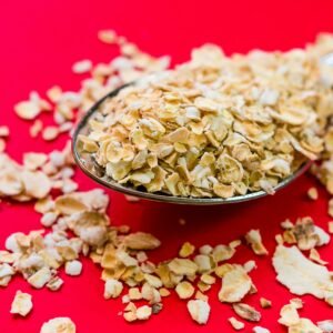 Close-up image of oats scattered on a spoon with vivid red background, perfect for food advertising.