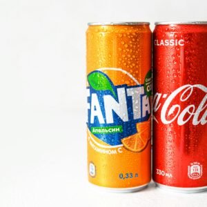 Close-up image of refreshing Coca-Cola and Fanta cans with water droplets.