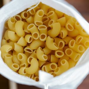 Overhead view of uncooked pasta in a white sack, emphasizing food and sustainability.