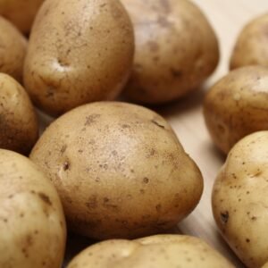 High-quality close-up photo of fresh raw potatoes on a wooden surface, ideal for food and culinary themes.
