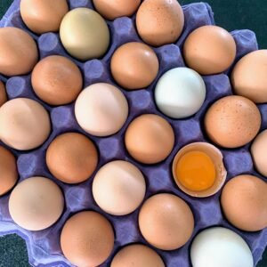 A top-down view of a tray filled with brown eggs, one cracked revealing the yolk.